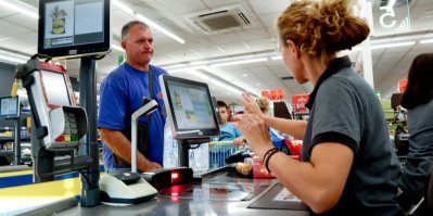 Žena za pokladnou v supermarketu a platící muž