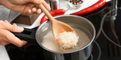 Žena vaří rýži v kastrolu na sporáku