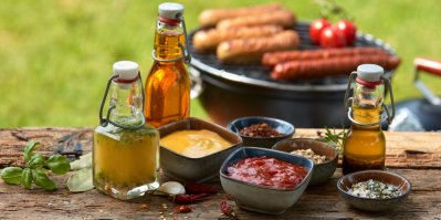 Různé koření a koření pro letní grilování na rustikálním dřevěném piknikovém stole