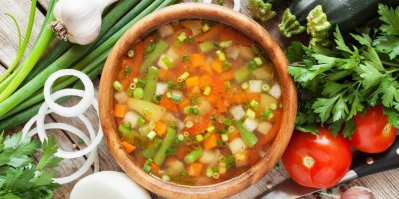 Zeleninová polévka v dřevěné misce a kolem přísady