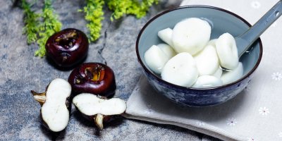 Vodní kaštany vedle a v mističce s vodou a lžicí