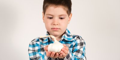 Chlapec drží česnek v dlaních a kouká se na něj