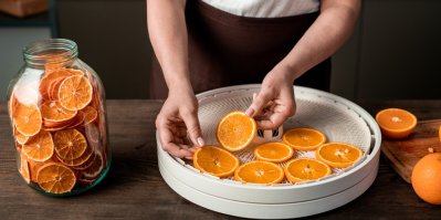 Žena dává pomeranče na sítko sušičky