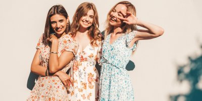 Tři usmívající se mladé ženy v květovaných šatech