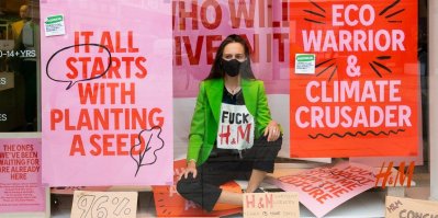 Demonstrující žena sedí ve výloze H&M