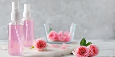 Dvě lahvičky s růžovou pleťovou vodou, světle růžové růže