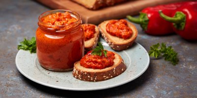 Ajvar ve sklenici, tři plátky chleba s ajvarem