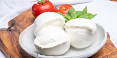 Bílé kuličky italského měkkého sýra mozzarella, podávané s lístky čerstvé zelené bazalky a červeným rajčetem