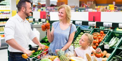 Otec, matka a malá dcera stojí v supermarketu u oddělení ovoce a zeleniny