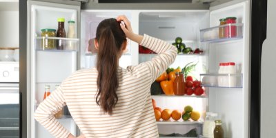 Žena se zamýšlí před otevřenou ledničkou