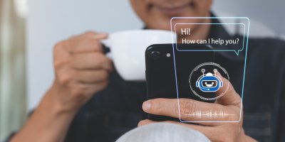 Muž s šálkem kávy komunikuje přes telefon s chatbotem