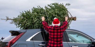 Muž dává vánoční strom na střechu auta