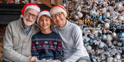 Prarodiče s vnoučkem ve vánočním oblečení před stromečkem