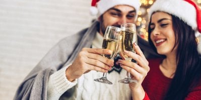 Muž a žena si připíjejí ve vánočních čepicích