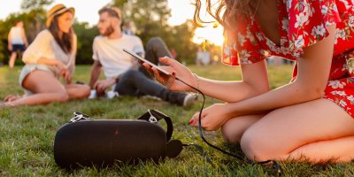 Žena s přáteli v parku spouští hudbu z reproduktoru