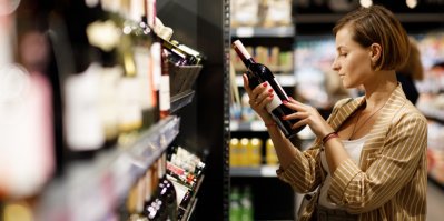Žena na obrázku vybírá víno v supermarketu