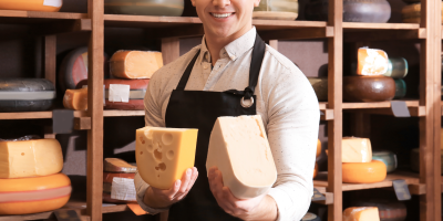 Muž drží dva zrající sýry