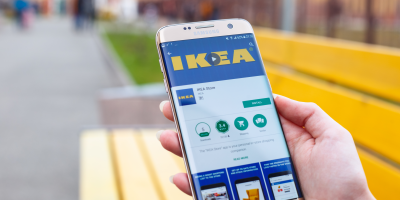 Člověk drží mobilní telefon, na kterém je otevřená aplikace IKEA