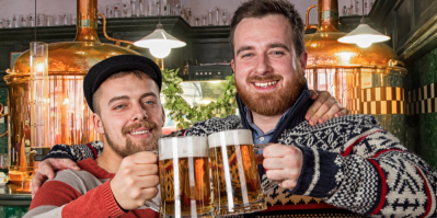 Dva muži si ťukají dvěma sklenicemi s pivem