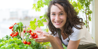 Žena drží rajčata na balkoně