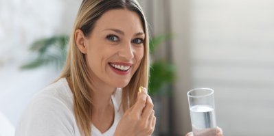 Usměvavá žena drží prášek a sklenici vody