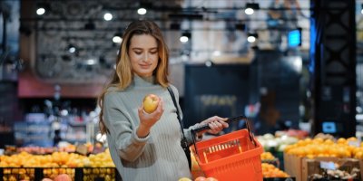 Žena čichá k jablku v supermarketu