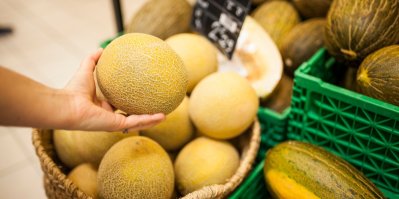 Ruka drží žlutý meloun v supermarketu