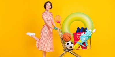 Žena s nákupním vozíkem s balony, vodní pistolí, nafukovacím kruhem a dalšími letními hračkami