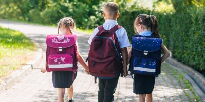 Tři děti jdou do školy s batohem na zádech