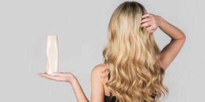 Žena s blonďatými vlasy drží šampon