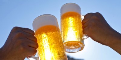Dva lidé si přiťukávají sklenicemi s pivem