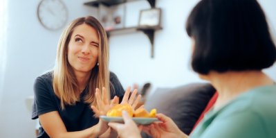 Žena nabízí druhé ženě talíř s jídlem, ta jej odmítá