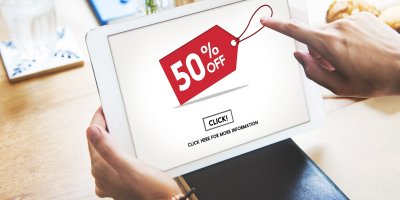 Člověk nakupuje na e-shopu, který si prohlíží na tabletu. Je na něm 50% sleva