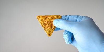 Ruka v rukavici držící chips, na kterém je vyobrazena lebka