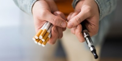 Ruce drží cigarety a elektronickou cigaretu