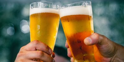 Dva lidé si přiťukávají sklenicemi piva