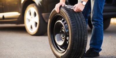 Člověk mění pneumatiku na silnici