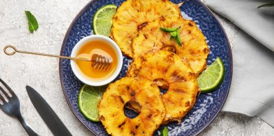 Grilovaný ananas na modrém talíři s miskou medu