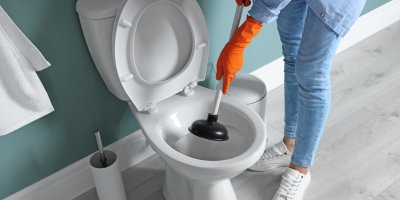 Člověk čistí WC zvonem