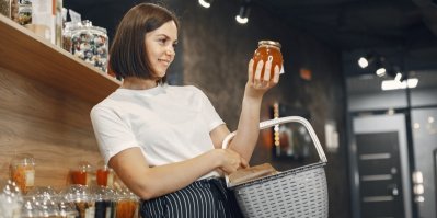 Žena s nákupním košíkem, která drží v ruce med