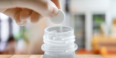 Ruka, která dává tabletu na čištění protézy do lahve