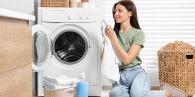 Žena si čichá k prádlu, které vyndala z pračky