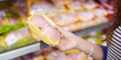 Žena v supermarketu, která drží v ruce kuřecí maso
