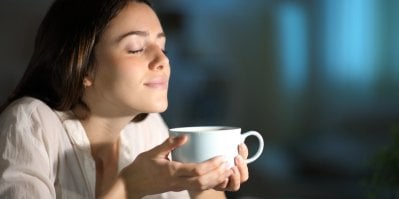 Žena se zavřenýma očima si čichá ke kávě