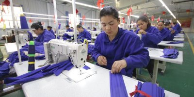 Ženy v modrém oblečení šijí v továrně