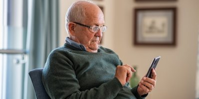 Starší muž si čte informace na mobilu