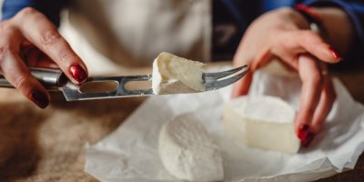 Žena, která krájí na kousky camembert