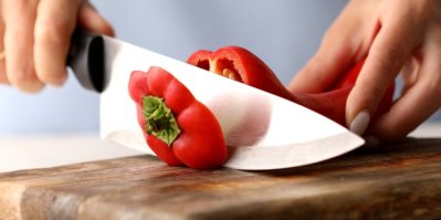Ruce krájí papriku na dřevěném prkénku