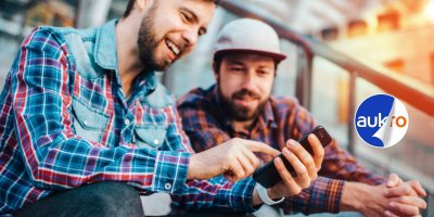 Dva muži v kostkovaných košilích se dívají do mobilu