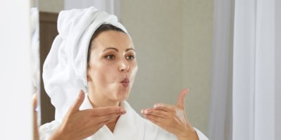 Žena s turbanem na hlavě cvičí obličejovou jógu